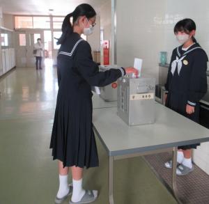 女子生徒が投票箱に投票用紙を入れている様子