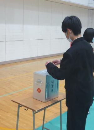 男子生徒が投票箱に投票用紙を入れている様子
