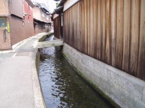 小川が建物と小路に挟まれて流れている写真1