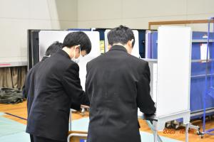 男子生徒3人が記載台で投票用紙を記入している様子