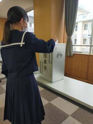 女子生徒が投票箱に投票用紙を入れている様子