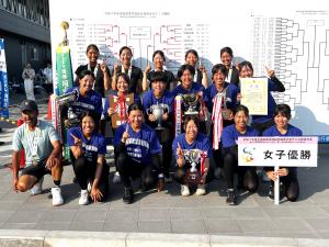 団体女子優勝のプラカードやトロフィ・賞状を掲げ笑顔で写真に写る野田学園女子テニス部のメンバー