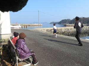 マラソン大会で走る男子生徒と応援する島民の様子
